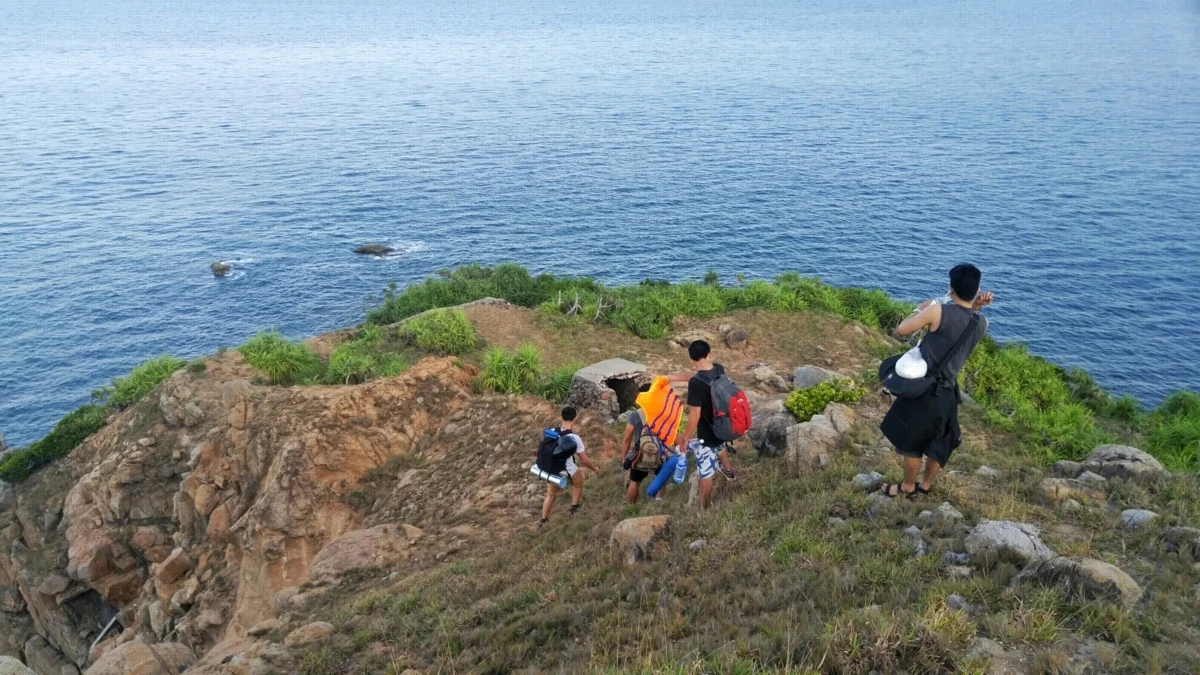 Du khách trekking trên con đường mòn khô ráo dẫn xuống Mũi Nghê mùa hè.