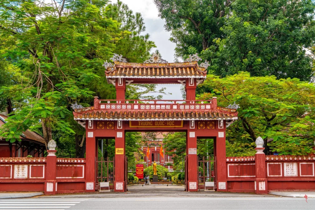 Ảnh trường Quốc Học Huế nhìn từ xa với sắc đỏ gạch đặc trưng bên dòng sông Hương
